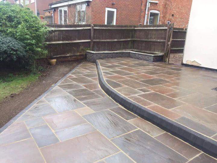 Dark porcelain patio wrapped around a house extension