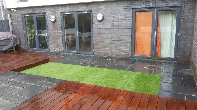 Rear terrace with decking, artificial lawn and dark stone paving