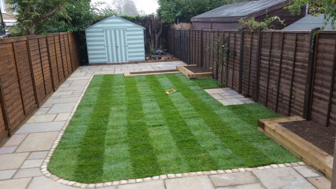 Striped lawn with sleeper planters and sandstone patio