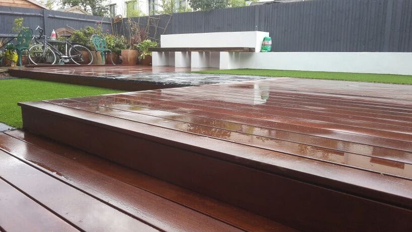 Raised hardwood decking meeting an artificial lawn