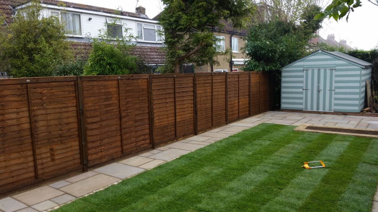 Close-board timber fencing with a striped lawn and shed