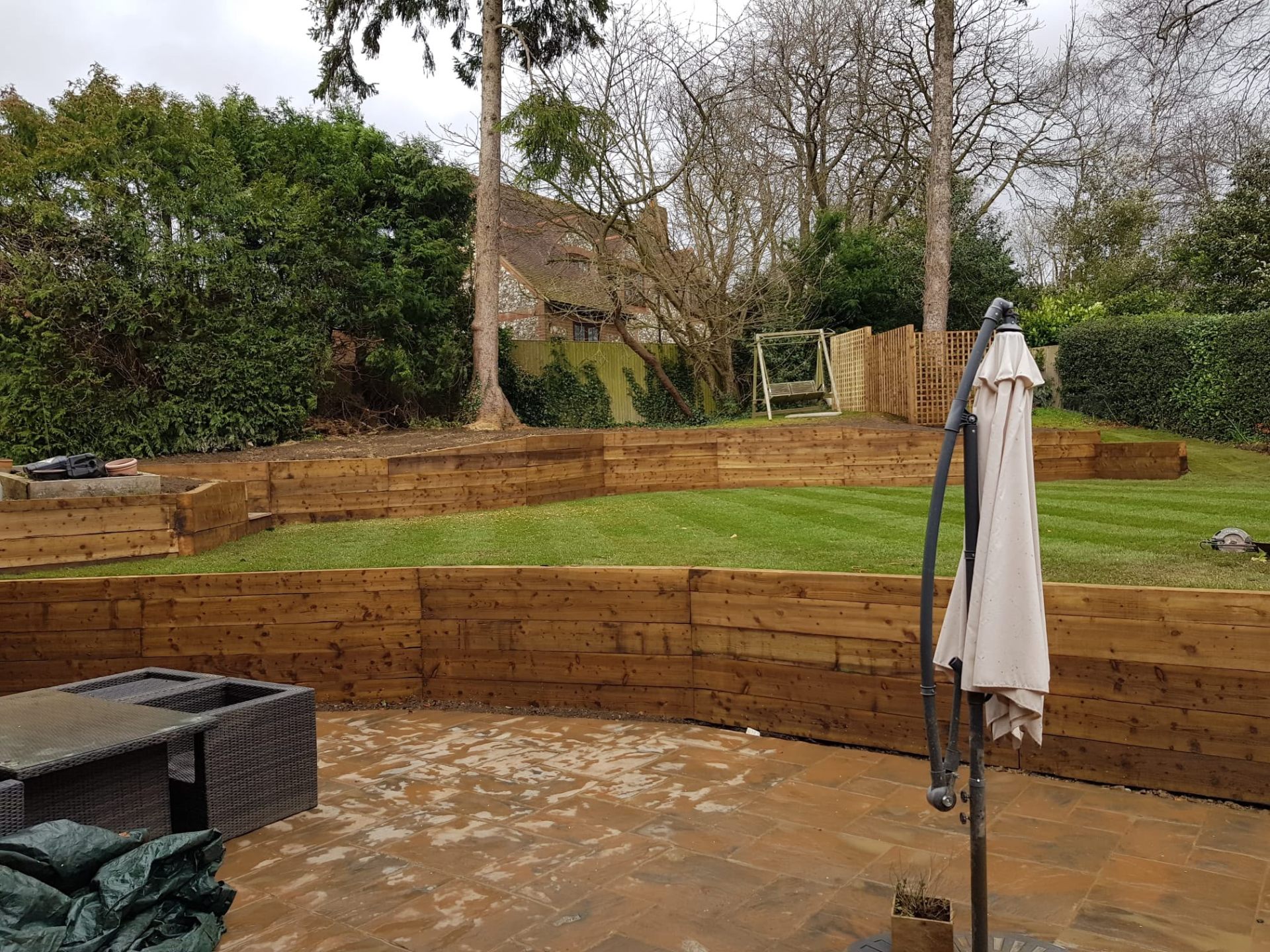Terraced sleeper retaining wall with lawn and patio