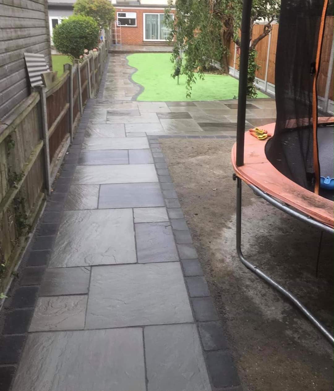 Dark stone path leading to a trampoline area