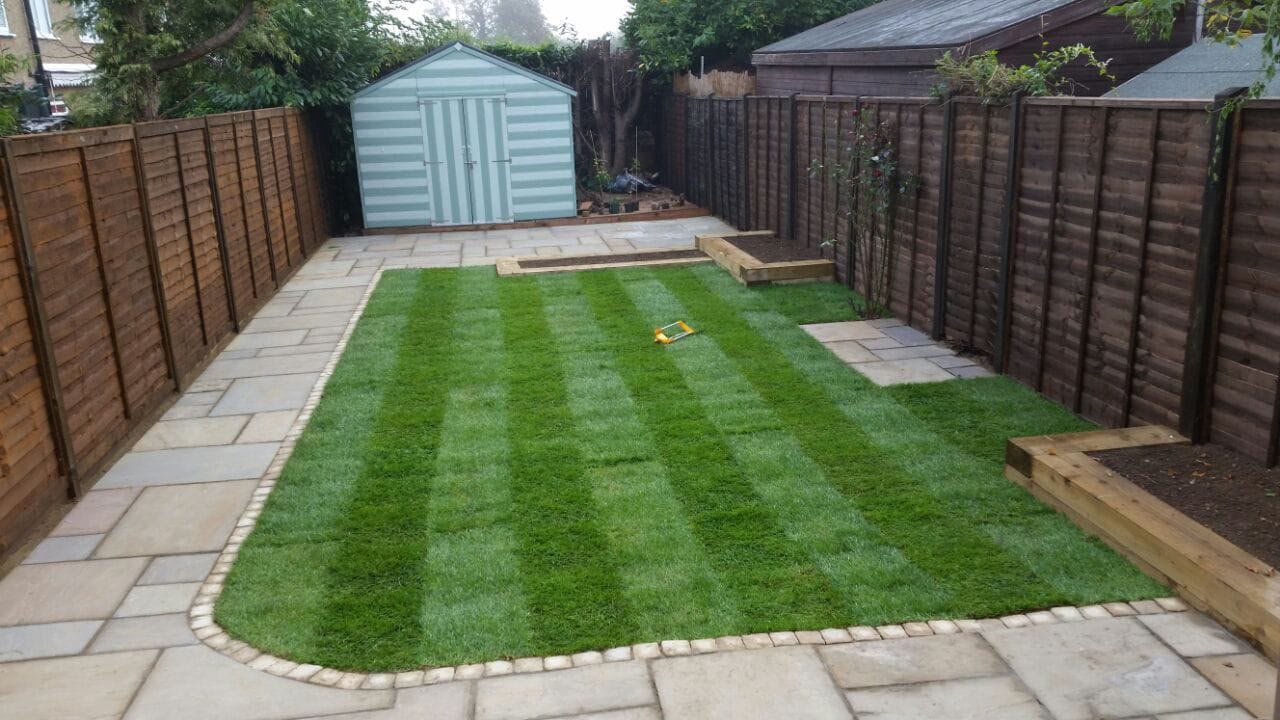 Striped lawn with sandstone edging and shed at the rear